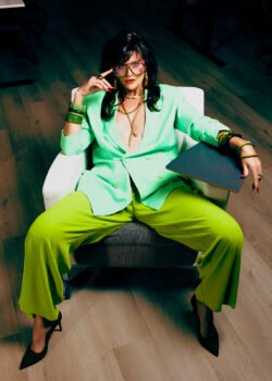 A woman in a green power suit sitting in an office chair. Karyn Rudance Creative Director