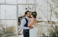 Hair styling for wedding - the bride and groom arm in arm in front of a glass building