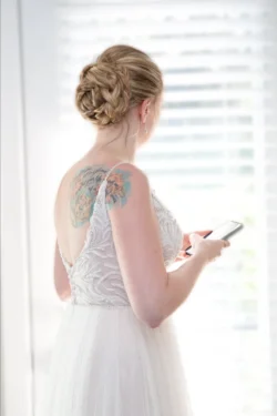 hair styling for wedding - bride with updo, with her back to the camera facing a window.