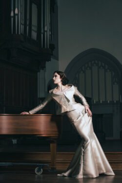 Editorial Photography - model leaning on a piano in a cathedral wearing a white dress. Creative direction by Karyn Rudance, Photography by Yvonne Hanson